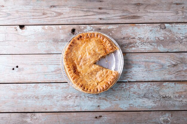 Photo directly above shot of baked stuffed pie sliced in plate on wooden table. unaltered, copy space, baked, sliced, and healthy food concept.