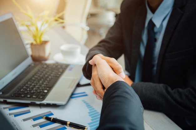 Photo directly above shot of business people shaking hands over documents at office desk