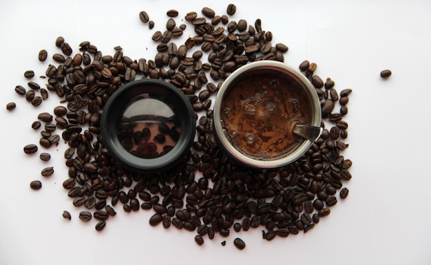 Directly above shot of coffee and beans with lens against white background