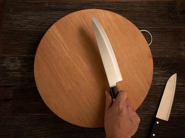 Photo directly above shot of person holding kitchen knife on wooden table