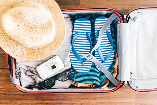 Directly above shot of personal accessories in suitcase on hardwood floor