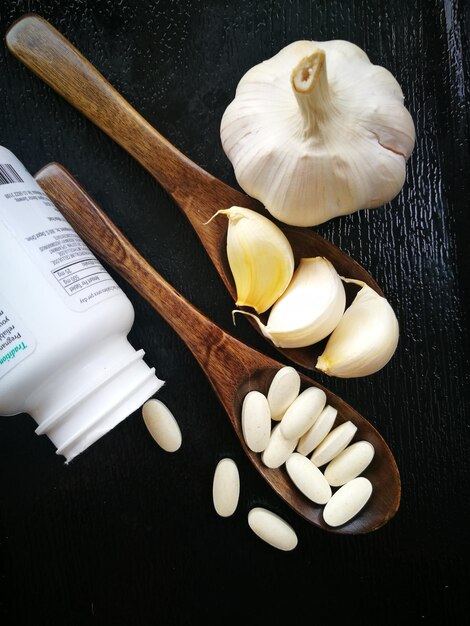 Photo directly above shot of pills and garlic in wooden spoons on table