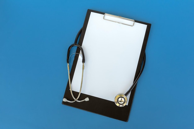 Photo directly above shot of stethoscope and clipboard against blue background