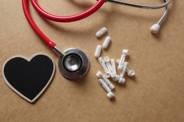 Directly above shot of stethoscope with heart shape and medicines on brown table