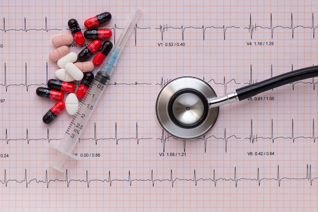 Photo directly above shot of stethoscope with pills and syringe on pulse rate