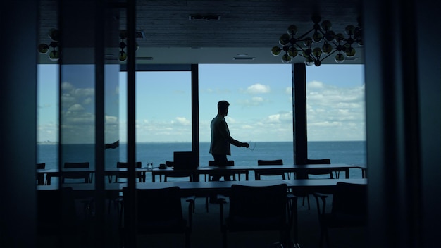 Director silhouette walking sea panoramic window Leader boss waiting in hotel