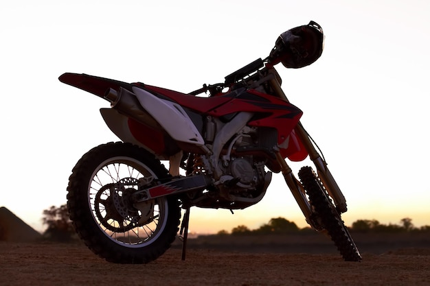 Dirt bike and sunset in desert for action danger competition fast race or speed training Off road motorcycle and helmet outdoor for fearless brave adventure adrenaline or extreme sport transport