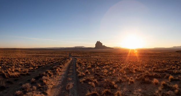 Dirt road in the dry desert with a mountain peak in the background