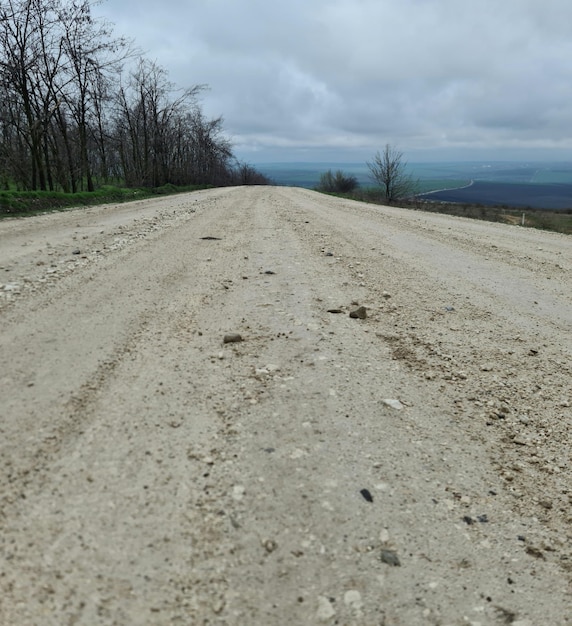 Photo a dirt road with a cloudy sky in the background