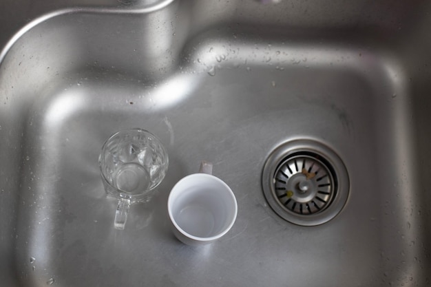 Dirty glass and ceramic cups in the sink,washing up