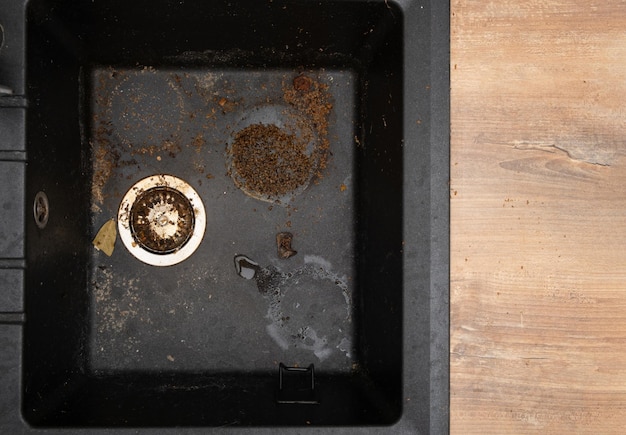 Dirty granite kitchen sink black with leftover bits of food Before House cleaning service