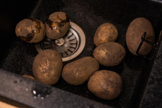 dirty potatoes in the sink preparing vegetables for washing at home