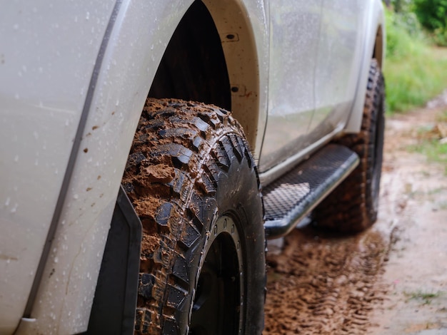 Dirty rear wheel of the off-road 4x4 truck at a countryside rural place in Rainy vibe, 4wd vehicle in rain, Selective focus shallow depth of field