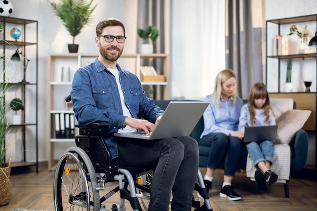 Disabled man and his family using laptops at home