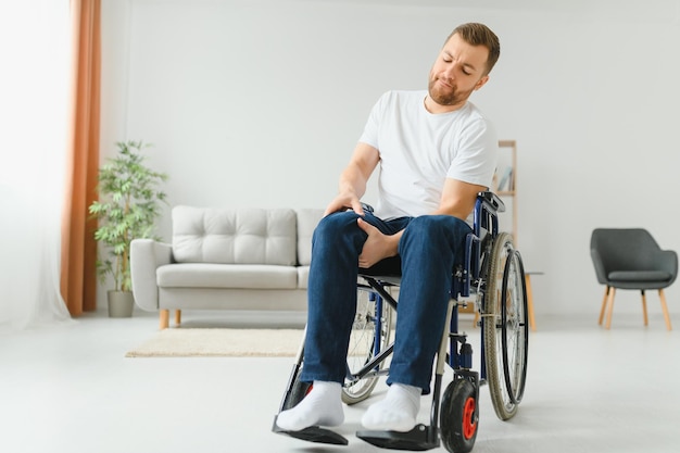 Disabled man at home tries to get to his feet in a wheelchair The concept of rehabilitation after injuries and car accidents