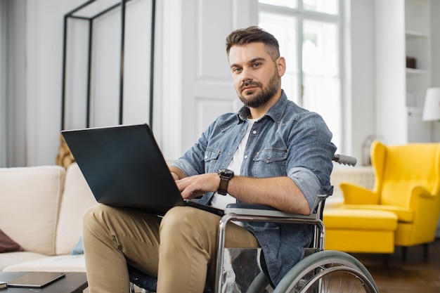 Disabled man sitting in wheelchair with laptop at home