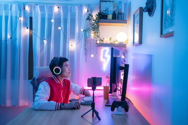 disabled man wearing red jacket headphones working computer room with neon light content creator