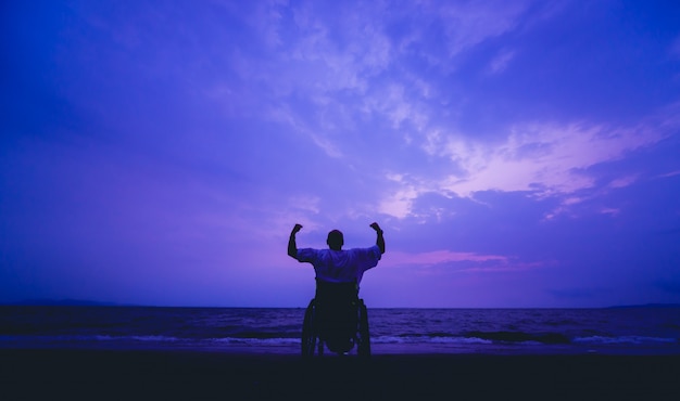 Disabled man in a wheelchair on the beach.