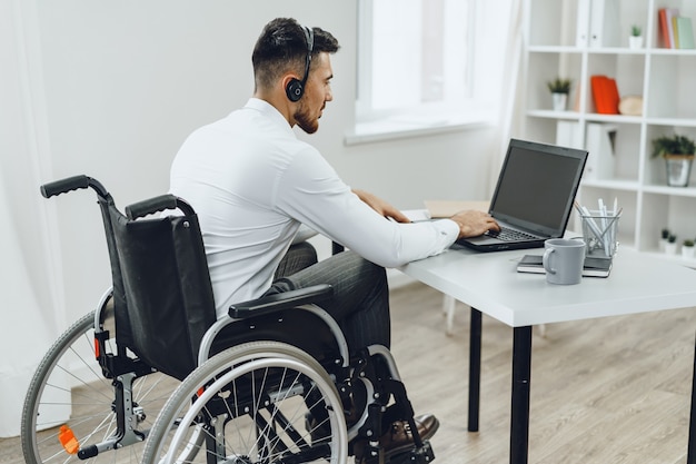 Disabled man in a wheelchair using laptop close up