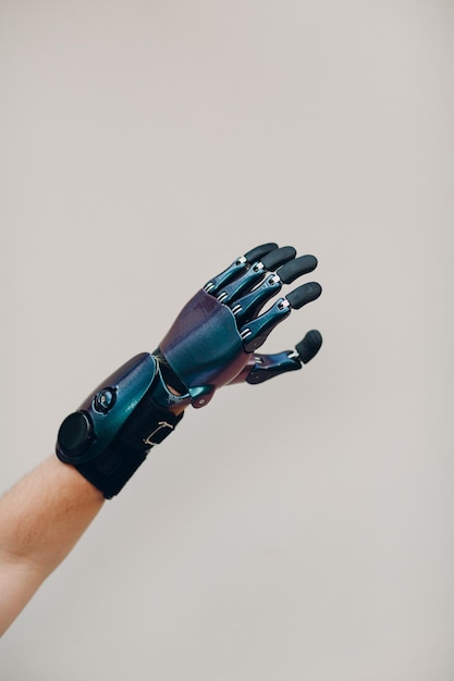 Disabled man with artificial prosthetic hand close up hand against gray background