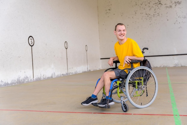 A disabled person in a wheelchair at a Basque pelota game fronton smiling