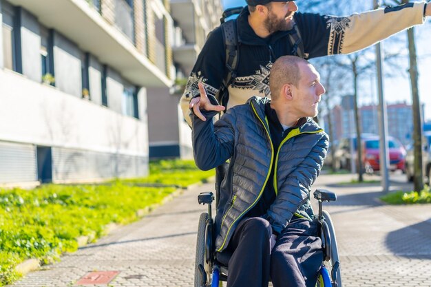 Disabled person in a wheelchair laughing with a friend in a chair on the street in winter