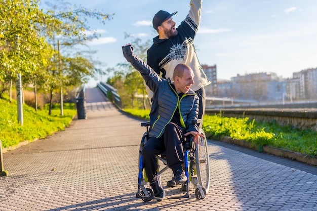 Disabled person in wheelchair with friend overjoyed smiling enjoying with arms up vistoria enjoying life