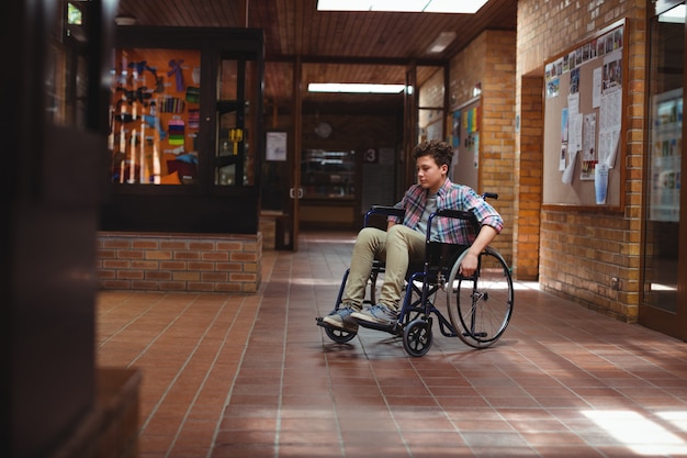 Photo disabled schoolboy on wheelchair in corridor at school