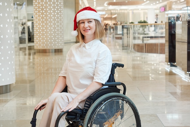 A disabled woman wearing a Santa hat, enjoying a Christmas sale in a shopping mall