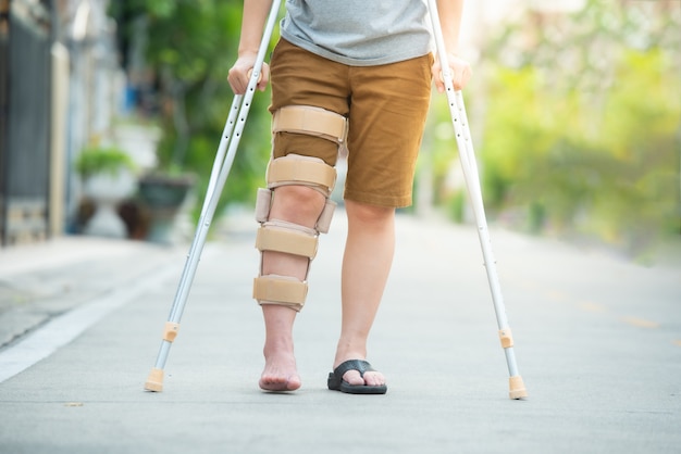 Disabled woman with crutches or walking stick or knee support standing in back side,half  body.