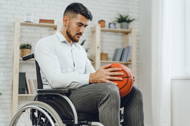 Disabled young man in wheelchair holding basketball ball