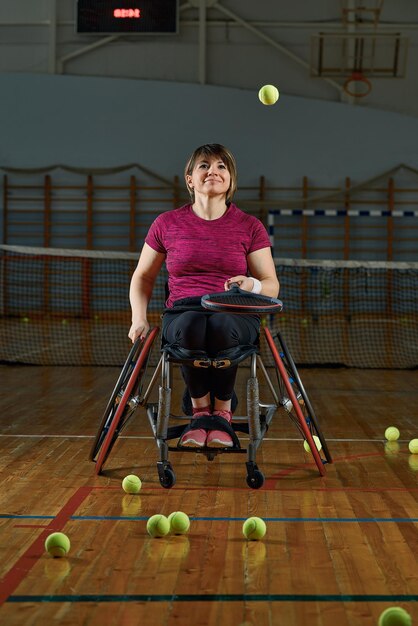 Disabled young woman on wheelchair playing tennis on tennis court