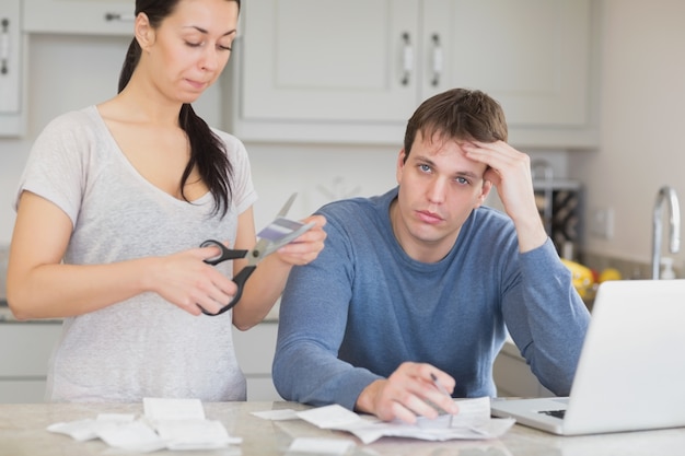 Disappointed woman cutting through a credit card