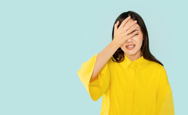 Disappointed young pretty woman face palm on blue studio background