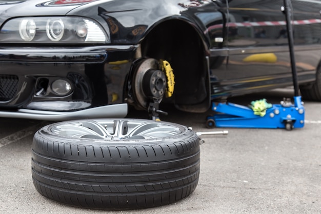 Disassembled car wheel in the foreground. 