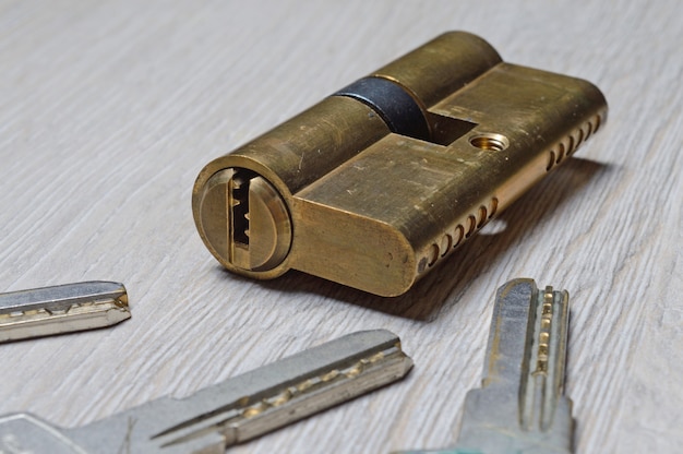 The disassembled door lock and the keys to it lie on a light surface. close-up.