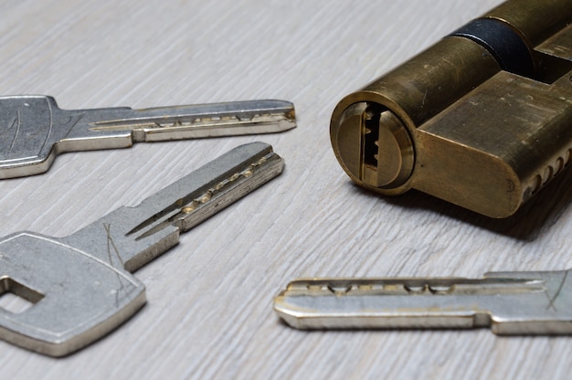 The disassembled door lock and the keys to it lie on a light surface. close-up.