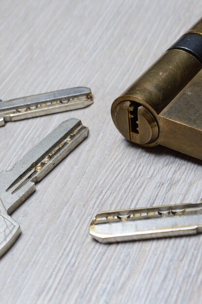 The disassembled door lock and the keys to it lie on a light surface. close-up.