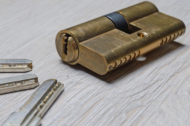 The disassembled door lock and the keys to it lie on a light surface. close-up.