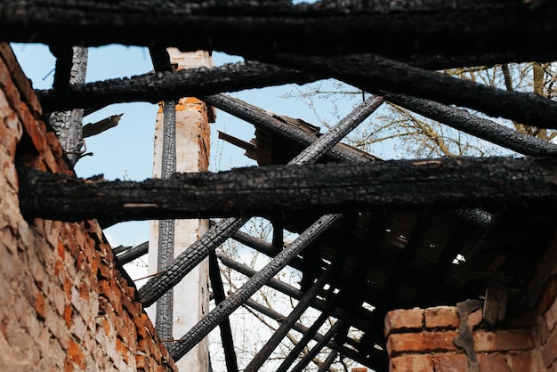 Disaster fiery house accident Burnt roof of an abandoned building coal logs and a red brick wall outdoors