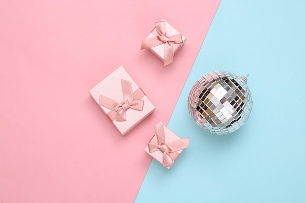 Disco ball and gift boxes on blue pink background Minimalism party and holiday concept