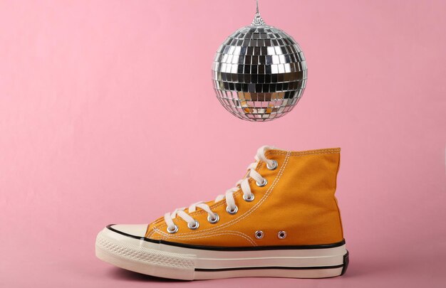 Disco ball and sneaker on pink background Minimalism party concept