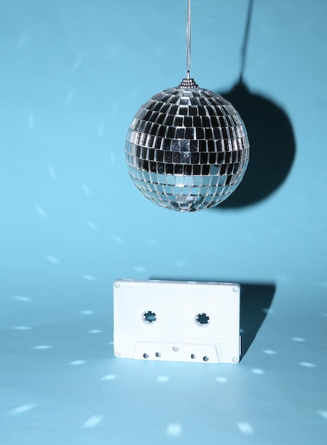 Disco ball with retro audio cassette on blue bright background Minimalism party concept