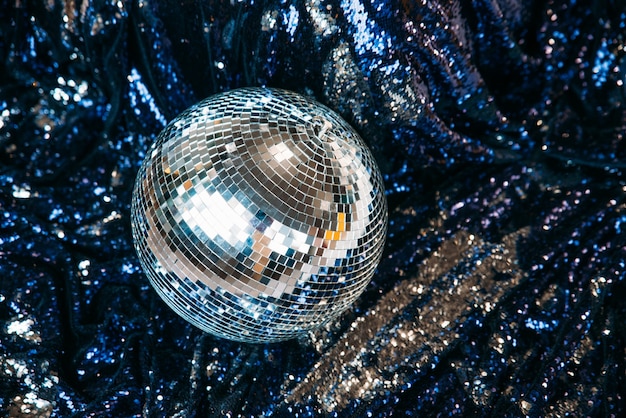 Photo a disco mirror ball lies on a blue textile with sparkles