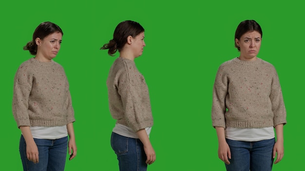 Discontent mad girl acting upset and displeased, posing over green screen background, being disappointed and discouraged. Sad female model standing over full body studio backdrop.