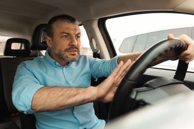 Discontented male driver beeping the horn driving car in city