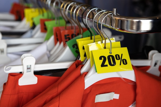 Discount sale tags, 20, 30, 50% off, on hangers with clothes in casual clothing store. Fashion concept, discount season, black friday, offline shopping, gimmicks, holiday sales.