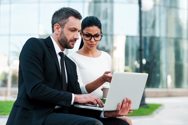 Discussing business project together. Two confident young business people working on laptop