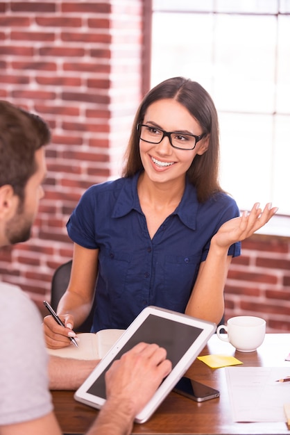 Discussing new creative project. Two cheerful business people in casual wear talking and gesturing while sitting face to face at the table