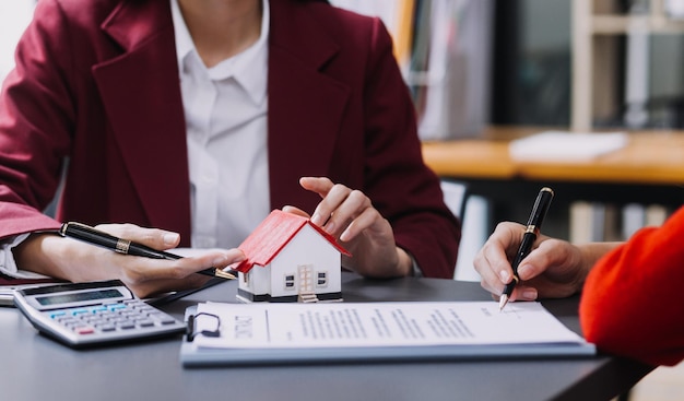 Discussion with a real estate agent House model with agent and customer discussing for the contract to buy get insurance or loan real estate or property